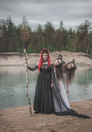 Beautiful witch with red hair and horned demons outdoorの写真素材