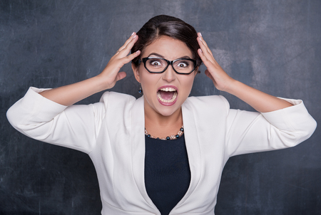 Angry beautiful brunette woman screaming and holding her headの写真素材