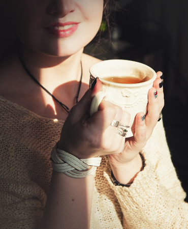 Young beautiful woman relax with cup of tea in sunlightの写真素材