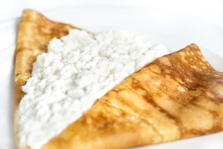 Thin delicious pancake with cottage cheese on white backgroundの写真素材