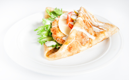 Thin delicious pancake with meat steak, cheese, tomato and greenery on white backgroundの写真素材