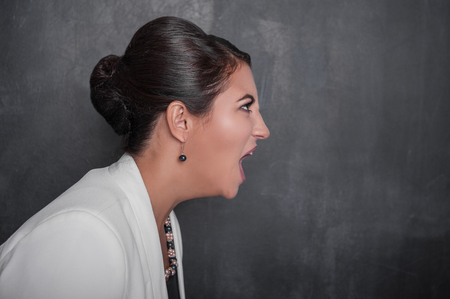 Angry screaming woman on chalkboard blackboard background. Side viewの写真素材