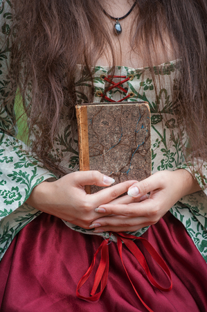 Hands of woman in medieval dress holding the old vintage bookの写真素材
