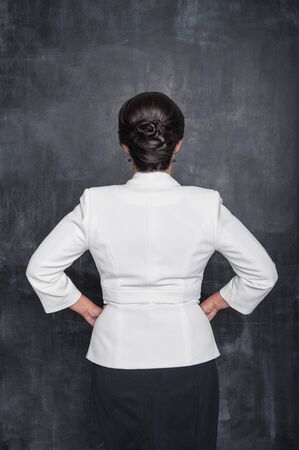 Business woman in white blazer standing back pose on chalkboard blackboard backgroundの写真素材