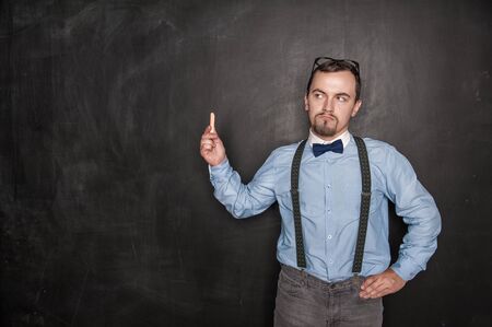 Thoughtful teacher with chalk on blackboard chalkboard backgroundの写真素材