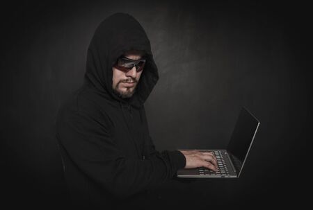 Man hacker programmer using laptop on dark background