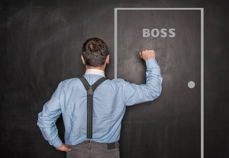 Business man knock by fist on boss door blackboard backgroundの写真素材