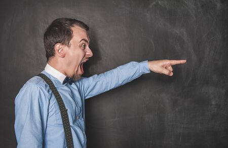 Angry screaming teacher man pointing out on blackboard backgroundの写真素材