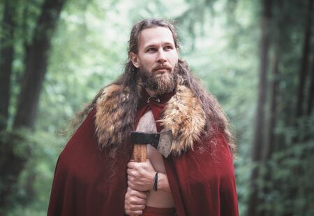 Warrior Viking man with iron axe standing outdoor