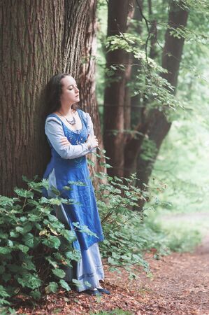 Young beautiful woman in blue medieval dress outdoorの写真素材