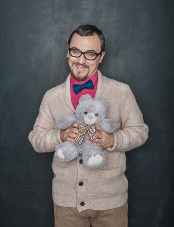 Funny man in retro style with teddy bear toy on blackboard chalkboard backgroundの写真素材