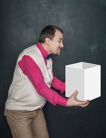 Funny teacher or business man holding empty box in his hands on blackboard backgroundの写真素材