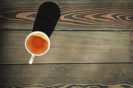 Cup of tea on old wooden floor background in sunlight