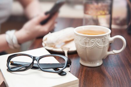 White cup of tea and eyeglasses on book on the table. Cozy home conceptの写真素材
