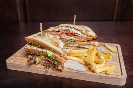 Club-sandwich with french fries on the wooden cutting boardの写真素材