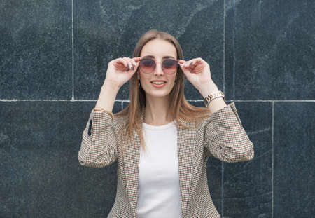 Beautiful young fashion stylish woman with eyeglasses on the wall city background