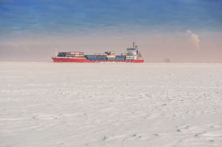 Winter shipping. Big cargo ship in frozen ice sea fairwayの写真素材
