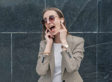 Beautiful young fashion stylish woman listening to music through wireless earphones