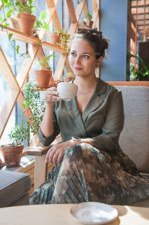 Beautiful young happy woman drinking coffee sitting in the cafe