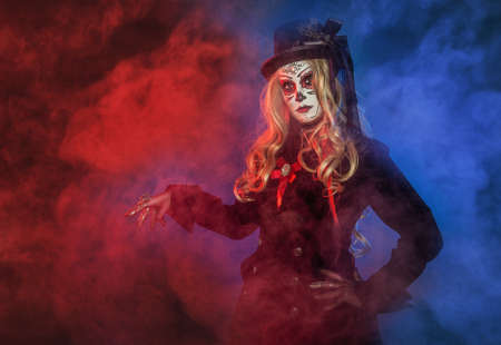 Beautiful woman with scary Halloween make up dead day calavera style on blue and red smoke backgroundの写真素材