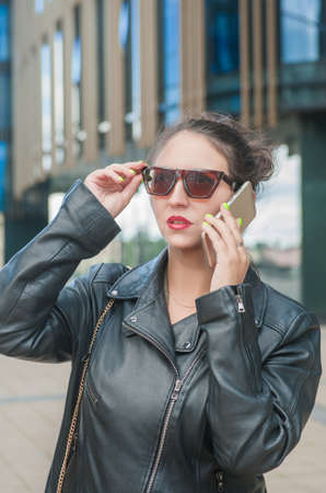 Beautiful stylish young woman in the city talking on mobile phone