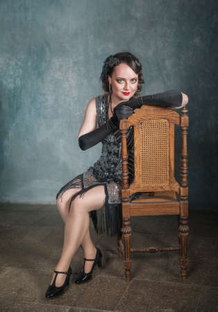 Portrait of beautiful elegant woman in retro 20 - 30 style sitting on the chair