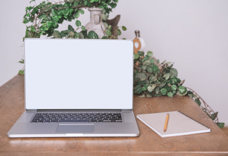 Open blank screen laptop on the table with notebook and pencil. Mock up design