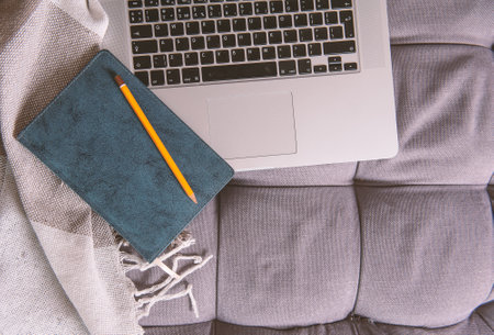Laptop, paper notebook and pencil on the sofa. Mock up design