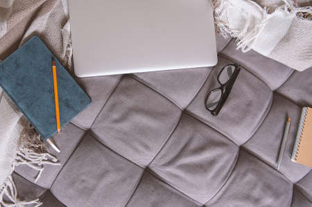 Laptop, paper notebook, pencil and eyeglasses on the sofa. Mock up designの写真素材