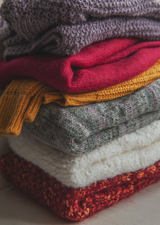 Autumn and winter background with folded in stack of knitted colorful sweaters