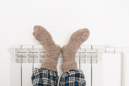 Man legs in wool socks warm on the radiator. gas crisis conceptの写真素材