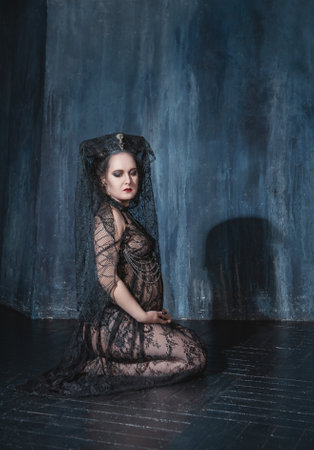 Beautiful demon style woman wearing black lacy dress sitting on the floorの写真素材