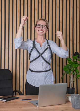 Angry screaming businesswoman standing near table with hands up in the officeの写真素材