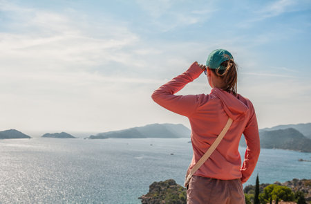 Beautiful traveler woman looking at the sea water in summer. Back pose
