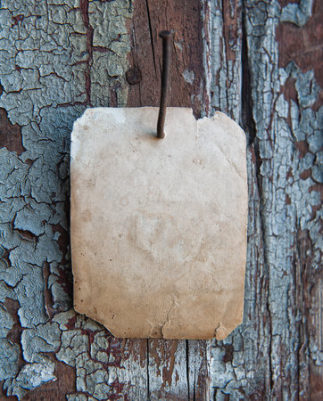 Old vintage paper advertisement hanging on aged wall nailed by rusty doornailの写真素材