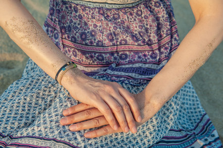 Sandy hands of beautiful woman wearing bracelets on the blue dress background
