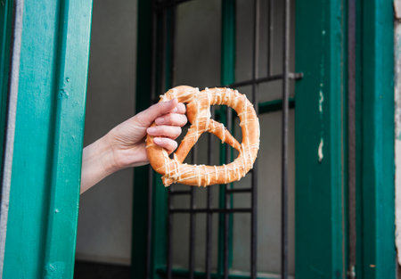 Delicious homemade pretzel treat showcased by a woman hand on the streetの写真素材