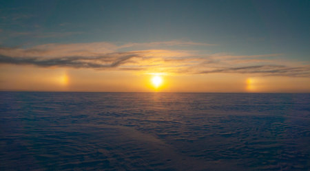 Halo effect around the sun during winter sunset over a vast snowy sea landscapeの写真素材