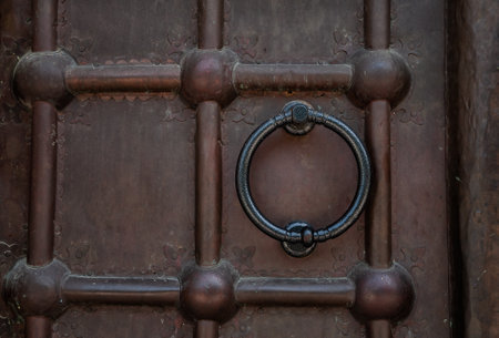 Close-up of an antique metal door with a vintage iron knocker, showing intricate craftsmanshipの写真素材