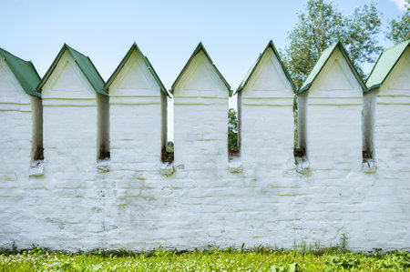 White stone medieval fortress wall with green roofs, showing historic architectureの写真素材
