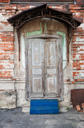 Weathered wooden door under an ornate iron canopy, highlighting vintage rustic charmの写真素材