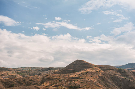 Majestic mountains of Armenia under a blue sky filled with clouds, showcasing natural beauty and rugged terrainの写真素材