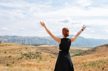 Beautiful woman enjoying the scenic Armenian mountains, arms raised in freedom and joyの写真素材
