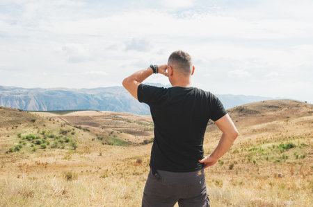 Back view of a solo traveler exploring a rural mountainous area under a serene skyの写真素材