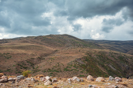 Dramatic mountain valley under a moody, cloudy sky with a rugged landscape