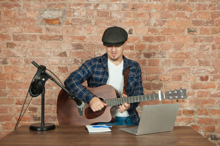 Musician recording acoustic performance singing and playing guitar with microphone and headphonesの写真素材