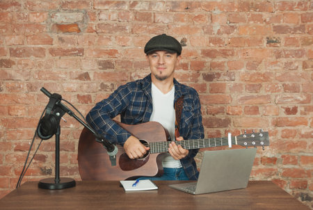 Musician recording acoustic performance singing and playing guitar with microphone and headphonesの写真素材