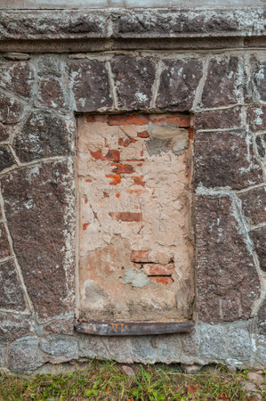 Weathered brick and stone wall with walled up window showcasing rustic texture and historic decayの写真素材