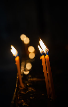 Soft bokeh lights surround the burning candle, creating a peaceful and spiritual atmosphereの写真素材