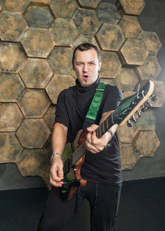 Intense electric guitarist performing with passion against a modern hexagonal backdrop